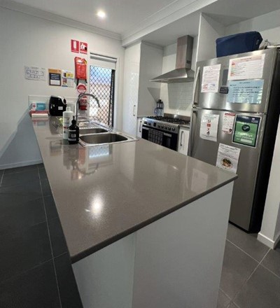 Kitchen with fridge, stove and oven in Lifestyle Solutions Supported Independent Living accommodation in Pallara, Qld